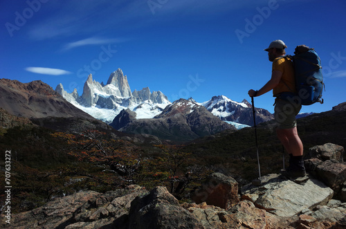 Hiking in Patagonia, Fitz Roy mountain, Man with big backpack standing on rocks with view of granite high peaks in Los Glaciares National Park in southern Argentina