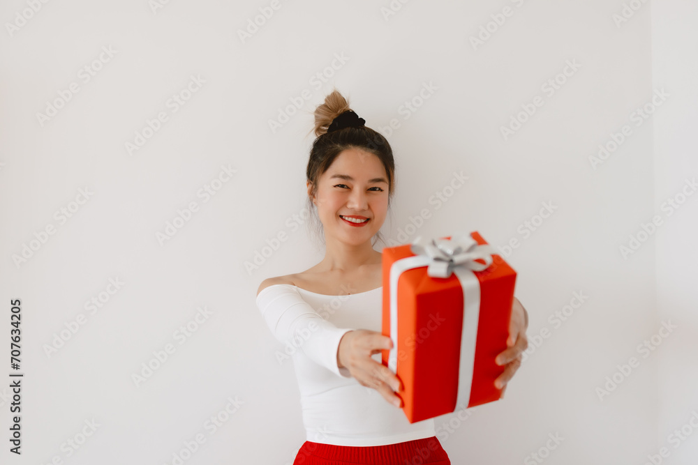 Beautiful asian Thai woman holding and presenting red gift present box, happy smiling standing isolated over white background wall, wear white top with red lips. Beautiful asian Thai woman holding and presenting red gift present box, happy smiling standing isolated over white background wall, wear white top with red lips.