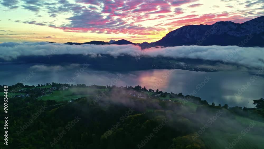 Aerial view of Attersee in Austria with low-lying colorful clouds at sunrise, lush green below Aerial view of Attersee in Austria with low-lying colorful clouds at sunrise, lush green below