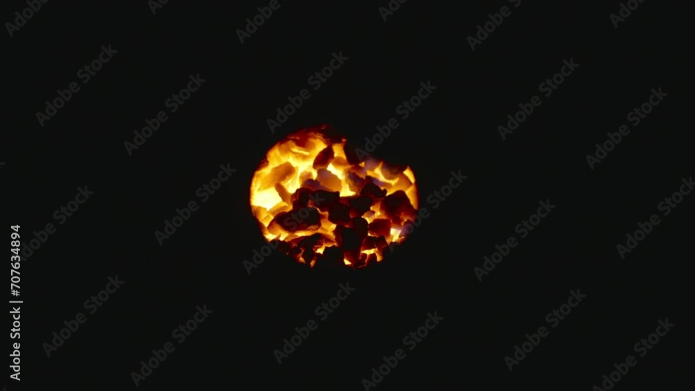 Coals of fire glowing in the dark through a hole, close up shot. Coals of fire glowing in the dark through a hole, close up shot.