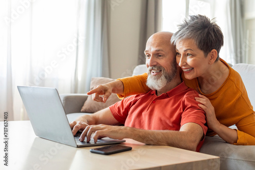 Digital Entertainment. Cheerful Elderly Couple Using Laptop At Home Together