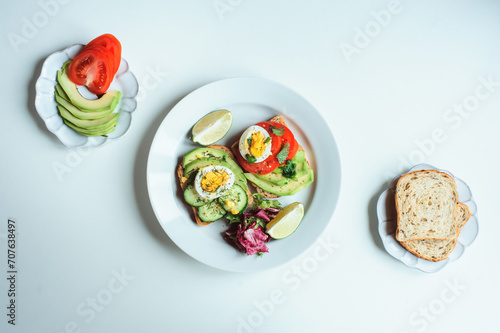 healthy vegetarian breakfast, avocado toast with cucumber, eggs, tomato and greean salad on wholegrain bread photo