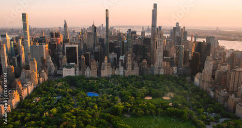 Evening New York City Aerial Landscape Over Central Park with Midtown Manhattan Skyscrapers. Cinematic Drone View of Urban Skyline with Sunset and Lightly Clouded Sky