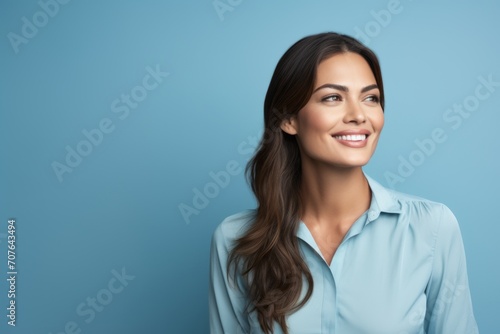 Portrait of happy smiling young businesswoman in blue shirt, over blue background