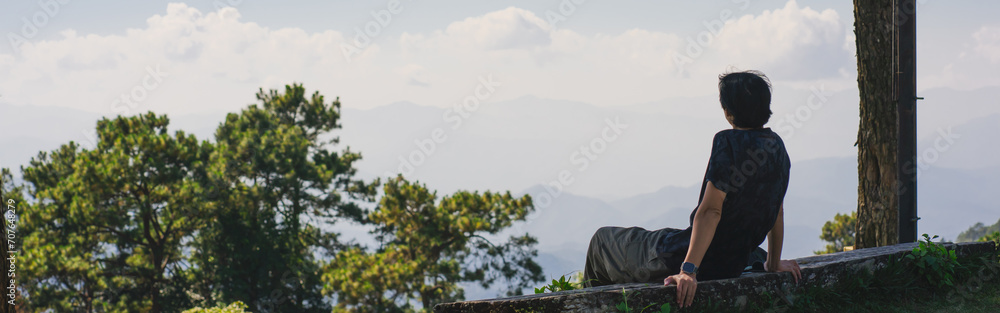 landscape and travel concept with solo freelancer man sit on wooden and use tablet work from outdoor with layer of mountain background