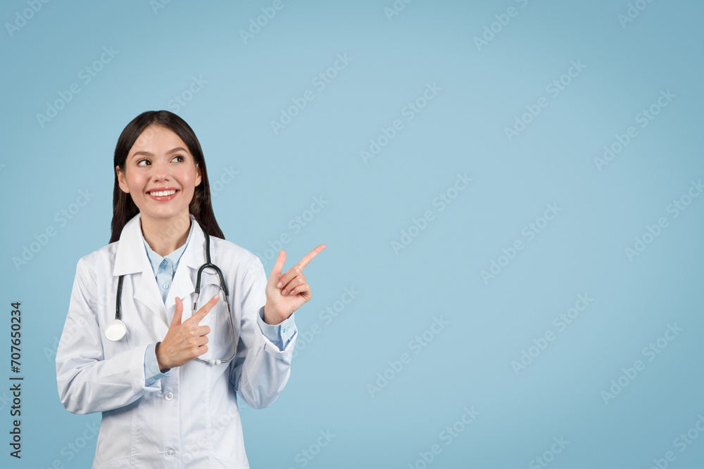 Woman doctor gesturing upwards with smile on blue background Woman doctor gesturing upwards with smile on blue background
