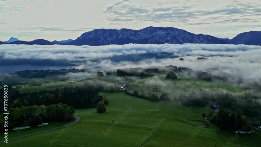Aerial view of a misty landscape with lush greenery and a mountain range in the background Aerial view of a misty landscape with lush greenery and a mountain range in the background