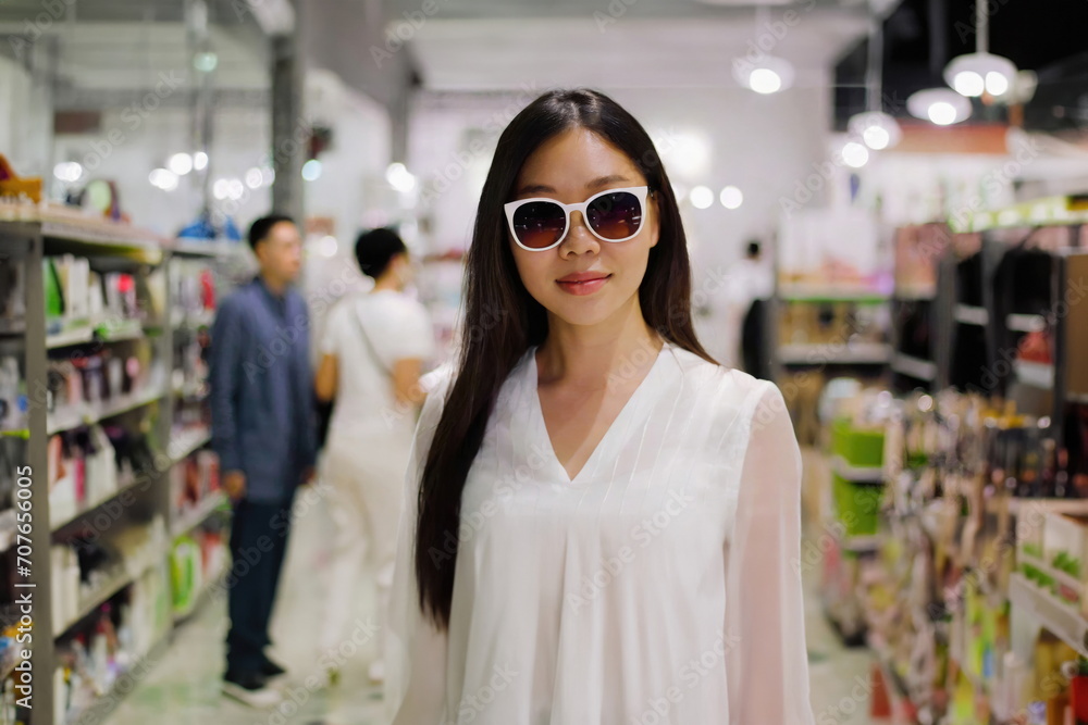 woman in white stands store wearing sunglasses woman in white stands store wearing sunglasses
