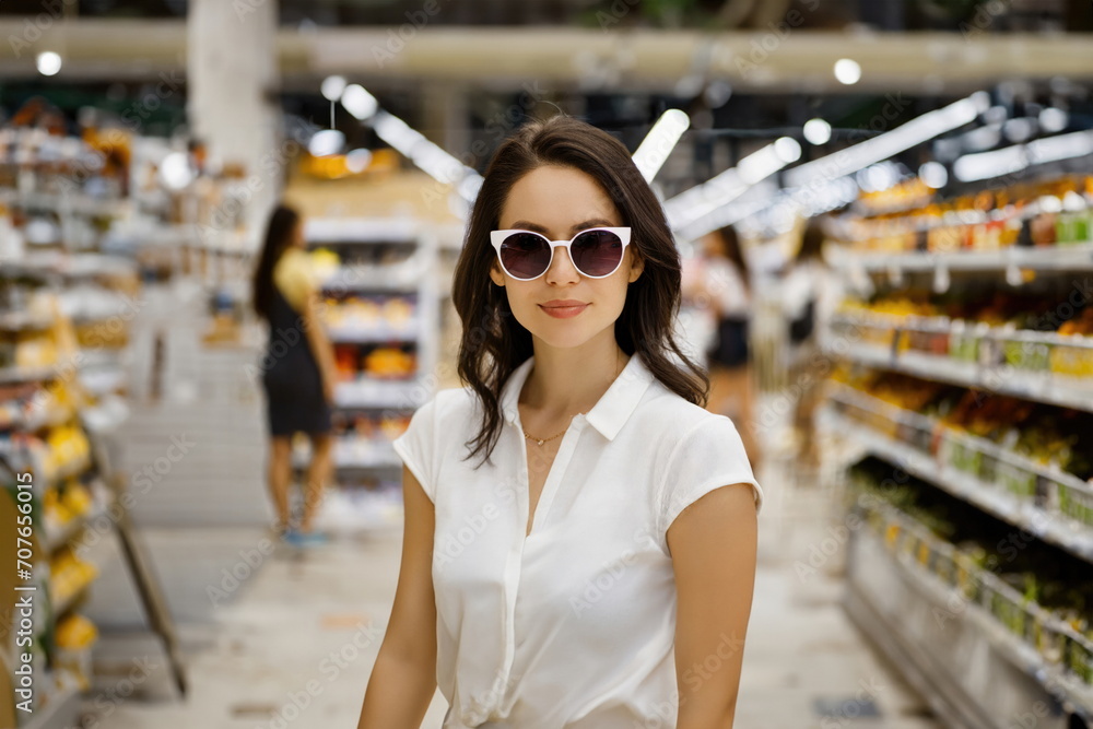 woman in white stands store wearing sunglasses