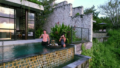 Young couple enjoying a floating breakfast at sunrise in a luxury infinity pool villa in Nusa Penida Bali Indonesia photo