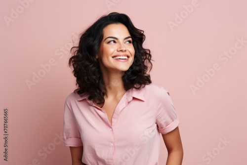 Portrait of happy smiling young woman in pink shirt, over pink background © Inigo