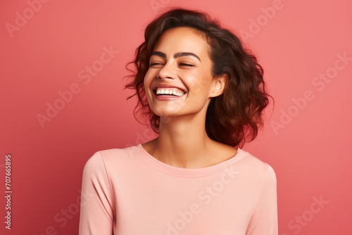Portrait of a beautiful young woman laughing and looking away against pink background