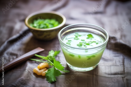 glass bowl of edamame soup with sprig of cilantro