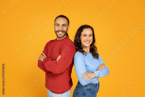 Confident young man and woman standing back to back