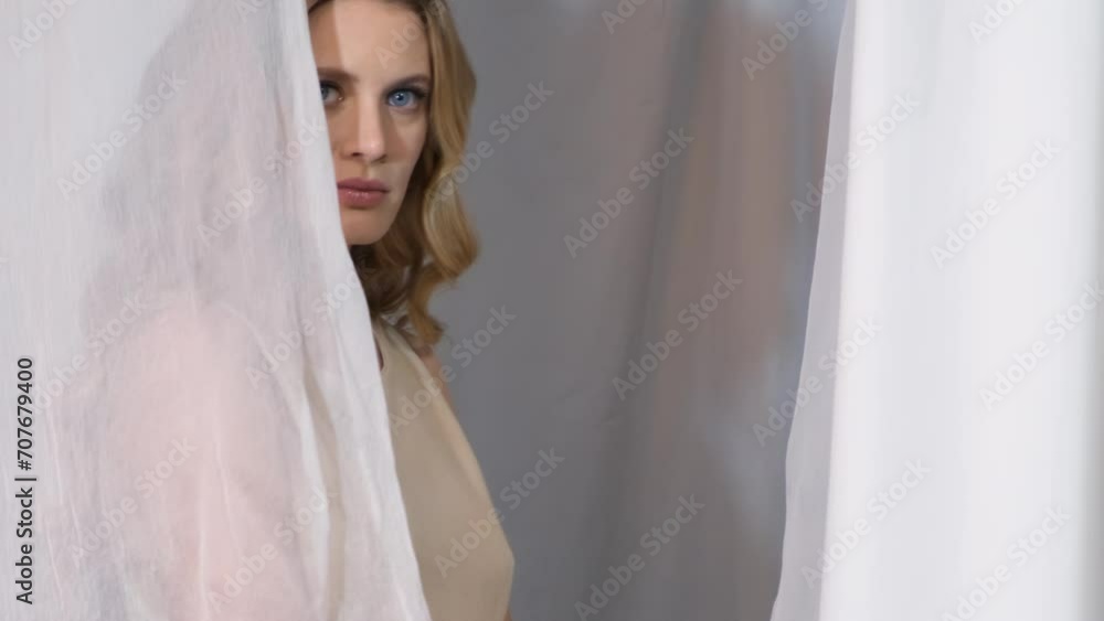 Slow motion video of woman covered with white mesh fabric. A woman hides her face behind a veil cloth. Slow motion video of woman covered with white mesh fabric. A woman hides her face behind a veil cloth.