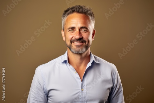 Handsome middle age man in a blue shirt over brown background. © Inigo