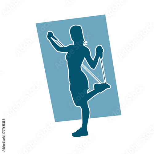 Silhouette of a sporty woman at gym workout using pull rope. Fitness exercise cords pull rope stretch resistance training.