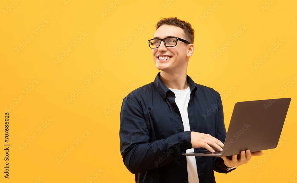 Cheerful young guy student using laptop, looking at copy space Cheerful young guy student using laptop, looking at copy space