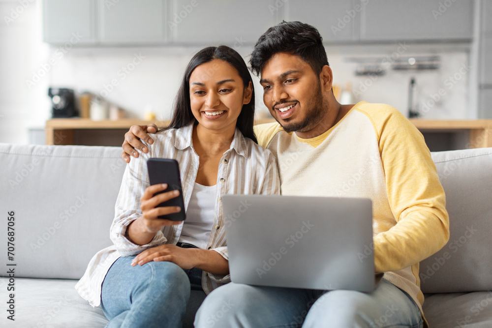 Happy Indian Couple Using Smartphone And Laptop Computer At Home Happy Indian Couple Using Smartphone And Laptop Computer At Home