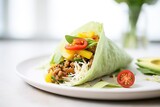 avocado and sprout taco in lettuce wrap on white plate