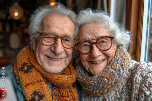 A happy elderly couple stand near the window, pose, take a selfie on the phone