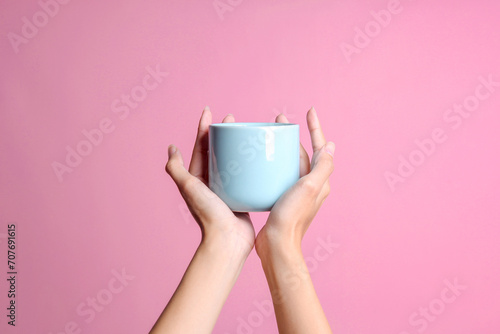 Woman hands holding blue cup mockup for text or branding isolated over pink background