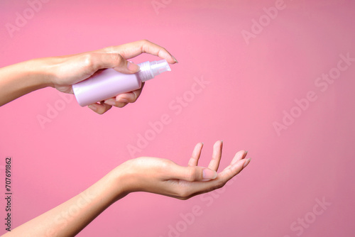 Woman holding spray sanitizer bottle mockup over pink background photo