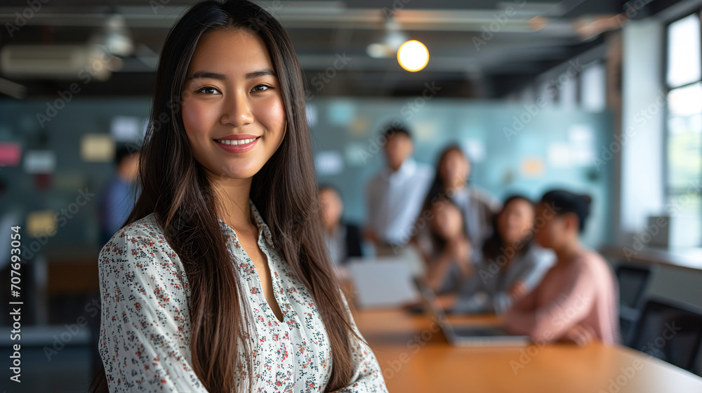 Confident Asian Businesswoman in Interactive Team Workspace Confident Asian Businesswoman in Interactive Team Workspace