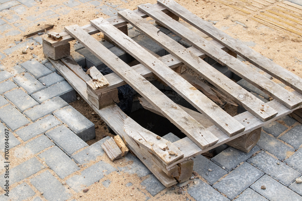 Hole in asphalt is covered with wooden pallet Hole in asphalt is covered with wooden pallet
