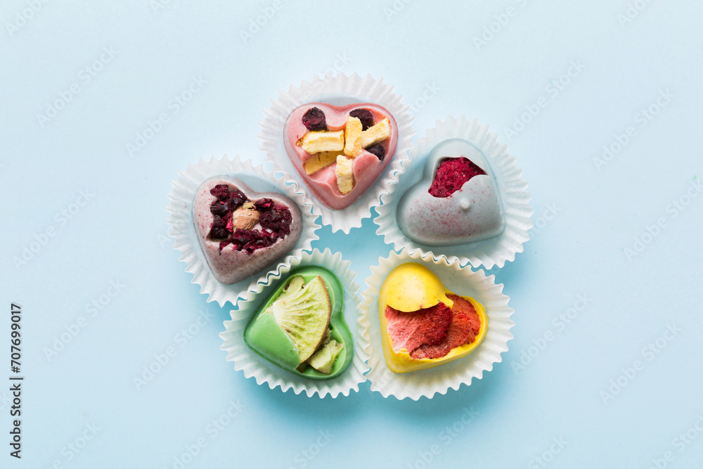 chocolate sweets in the form of a heart with fruits and nuts on a colored background. top view with space for text, holiday concept chocolate sweets in the form of a heart with fruits and nuts on a colored background. top view with space for text, holiday concept