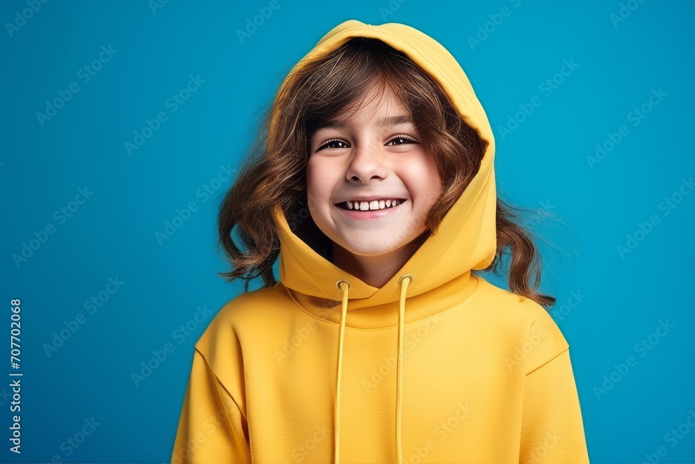 Portrait of a smiling little girl in yellow hoodie on blue background Portrait of a smiling little girl in yellow hoodie on blue background