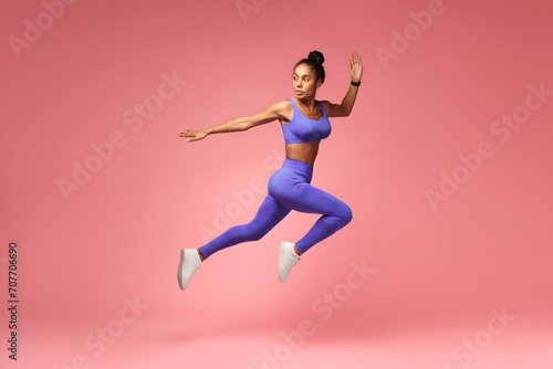 Athlete african american lady jumping having workout on pink background