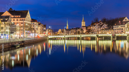 Night cityscape with Limmat river of the historical Zurich city, Switzerland.Panoramic view of historic Zurich city center with famous Fraumunster Church and river Limmat at Lake Zurich ,in twilight. photo