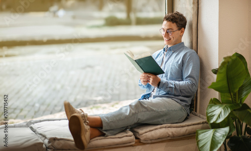 Focused calm smart european young man student in glasses read book, enjoy peace photo