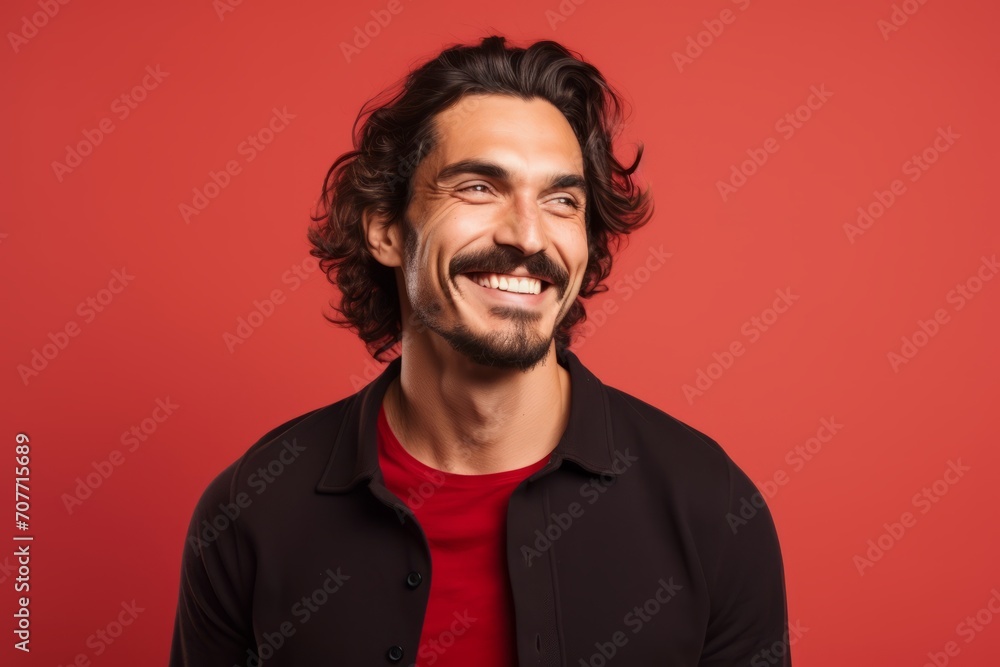 Portrait of handsome young man laughing and looking at camera over red background