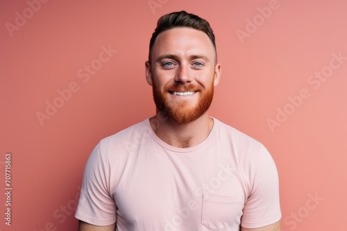 Portrait of a handsome young man smiling while standing against pink background