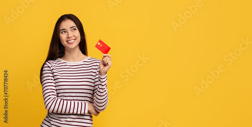 Positive young asian lady showing bank credit card photo