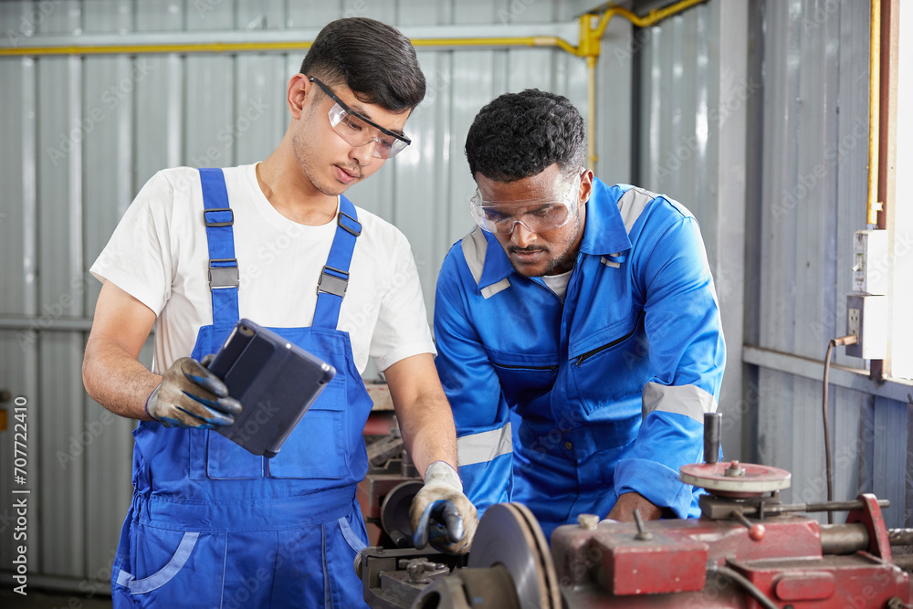 workers or technicians working on tablet beside lathe machine in the factory workers or technicians working on tablet beside lathe machine in the factory
