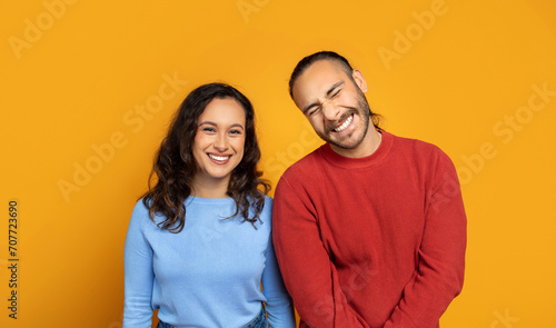 Cute millennial couple posing together on orange background