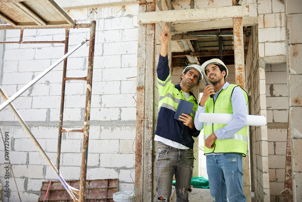 workers or architects working on tablet and pointing up to something at construction site workers or architects working on tablet and pointing up to something at construction site