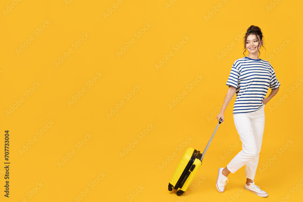 A young girl with a yellow suitcase on a yellow background A young girl with a yellow suitcase on a yellow background
