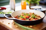mid-stir kung pao chicken in skillet with vegetables