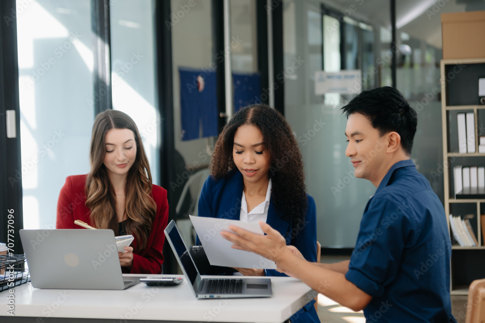 Office colleagues have a casual discussion. During a meeting in a conference room, a group of business teem sit in the conference room