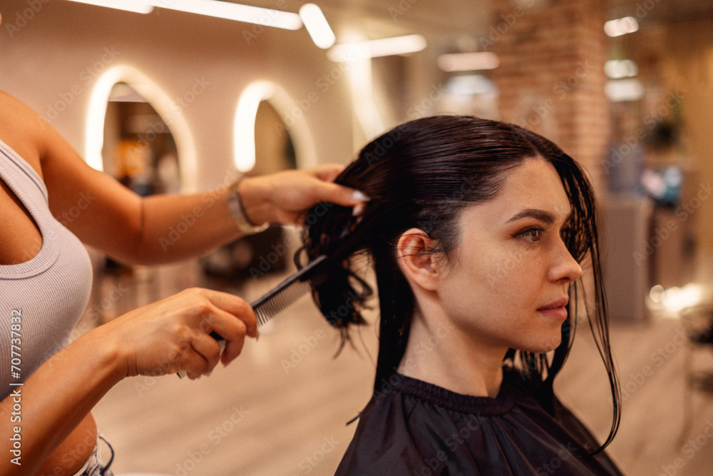 Fototapeta premium hairdresser cuts hair of woman while working in beauty salon