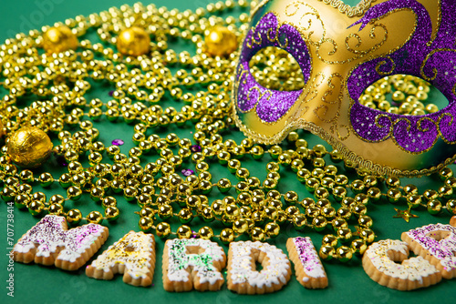 Mardi Gras King Cake Cookies, Carnival Masks, Gold Beads on Green Background.