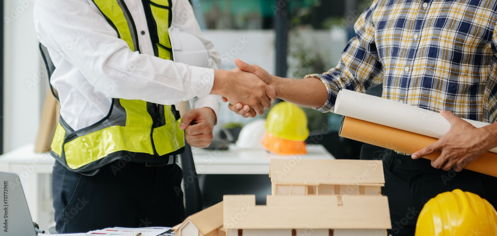 Engineer desk with object paper and tablet with blurry engineer teamwork hardworking to consults about their building project.. Engineer desk with object paper and tablet with blurry engineer teamwork hardworking to consults about their building project..