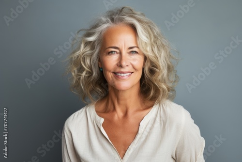 Portrait of a happy mature woman smiling at the camera against grey background