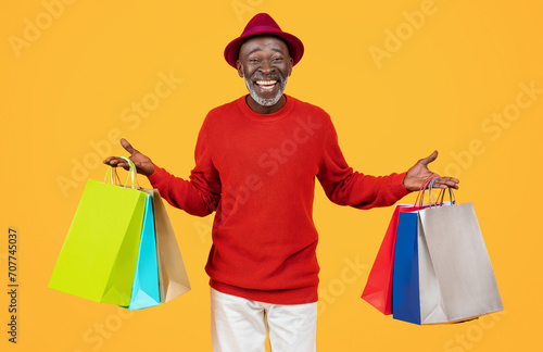 Delighted elderly black man with a bright smile, wearing a red sweater and stylish hat