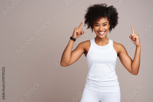 Concept of workout and fitness. Smiling fit and healthy african-american female athelte, wearing white uniform, pointing fingers up and showing logo, beige background photo