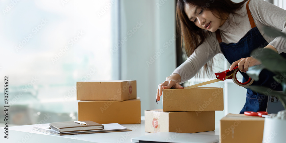 Young business entrepreneur sealing a box with tape. Preparing for shipping, Packing, online selling, e-commerce concept Young business entrepreneur sealing a box with tape. Preparing for shipping, Packing, online selling, e-commerce concept